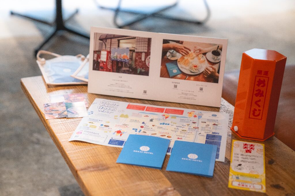 宿泊者と地域の店舗をつなぐ「SEKAI PASS」と「館内マップ」、名物の開運おみくじも用意